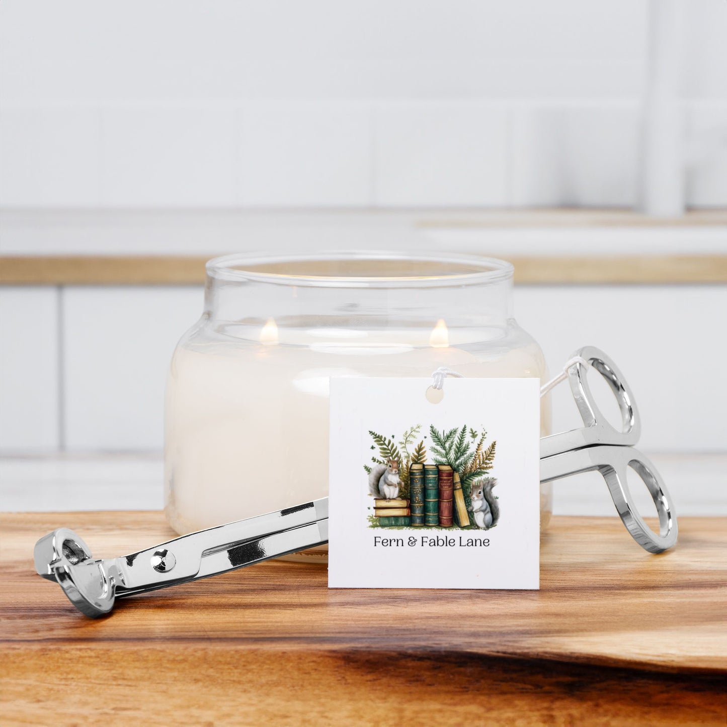 Wick trimmer and glass candle jar with a decorative label on a wooden surface