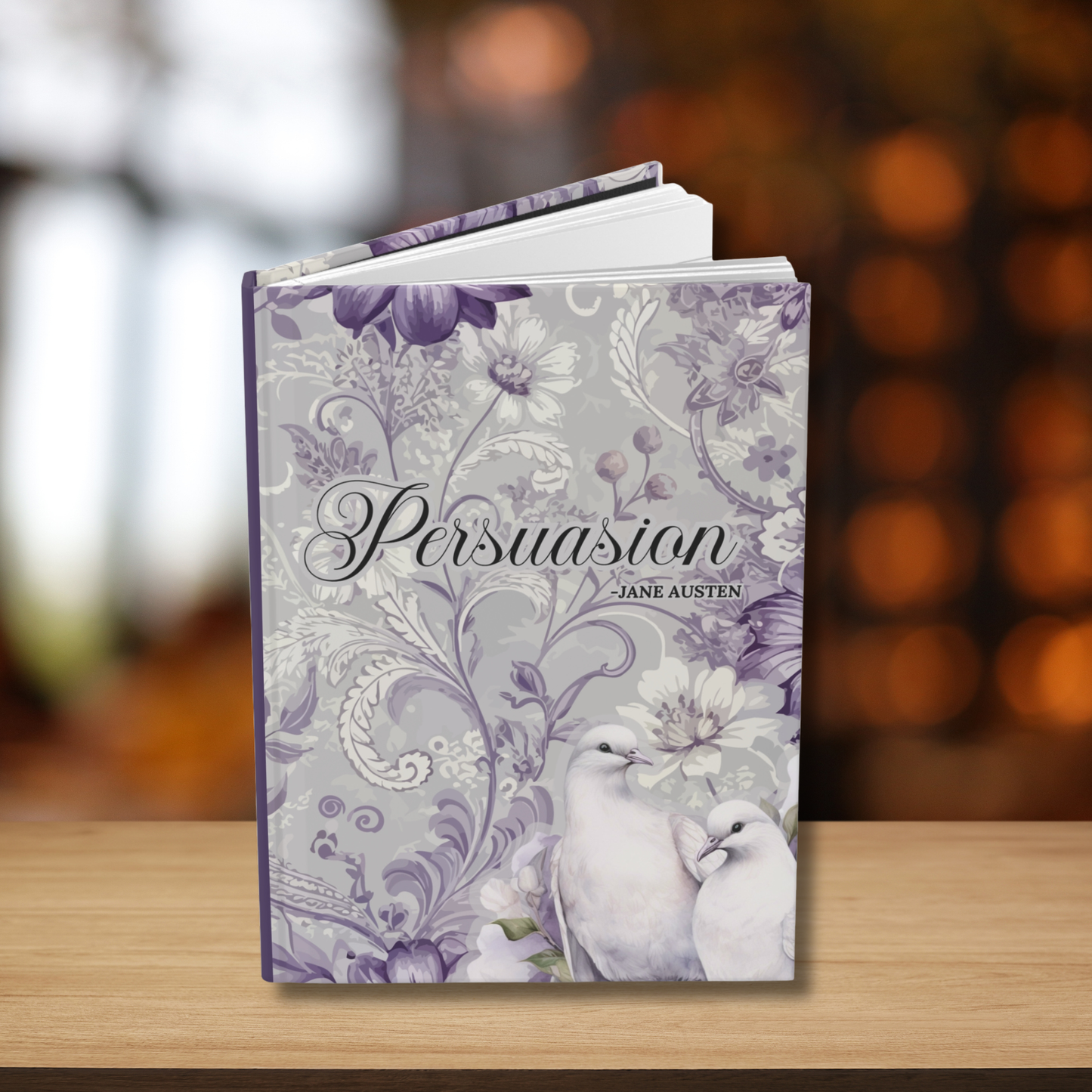 Journal titled 'Persuasion' by Jane Austen with floral design on a wooden surface