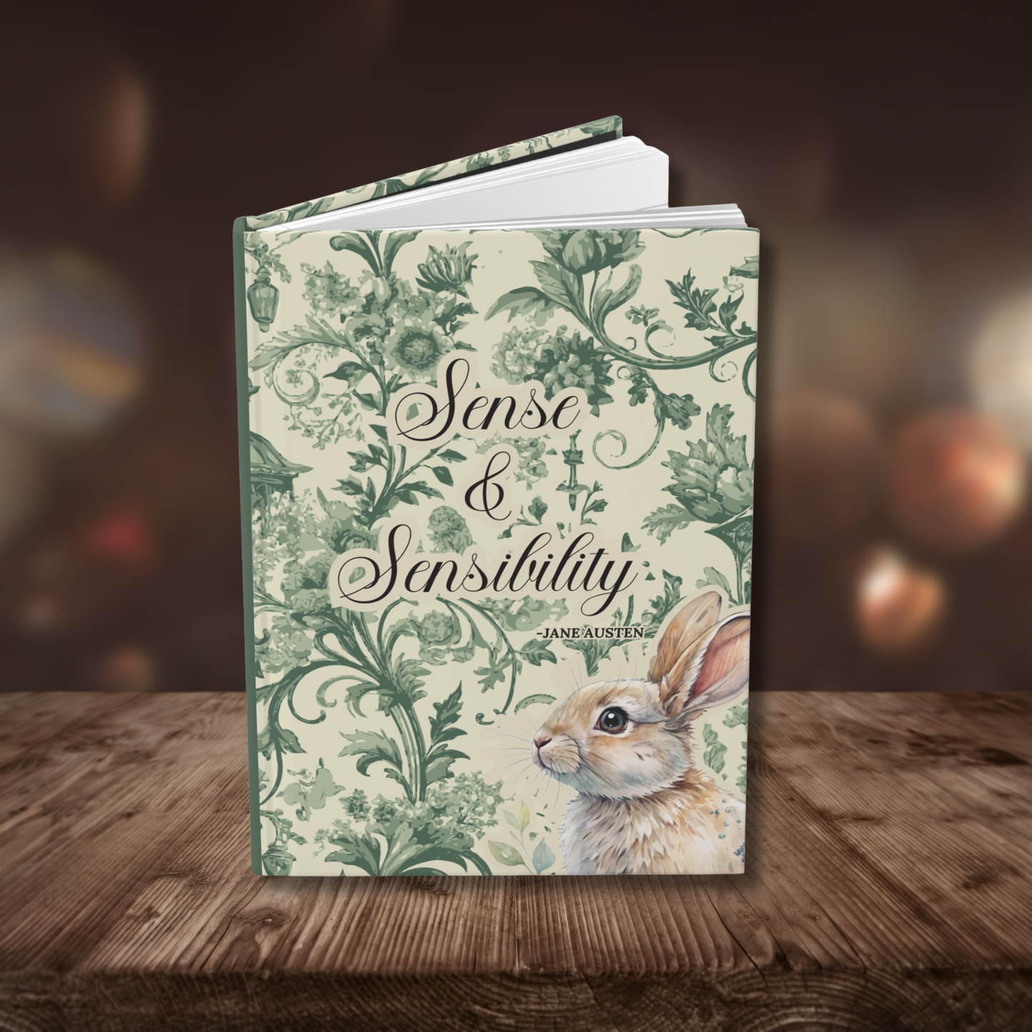 Journal cover with 'Sense & Sensibility' on the front. Green toile design and rabbit illustration on a wooden surface.