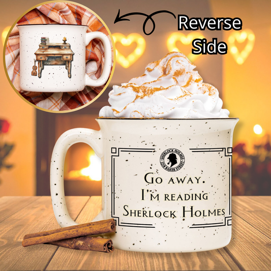 White mug with text 'Go away, I'm reading Sherlock Holmes' on a wooden table with hot chocolate and whipped cream.