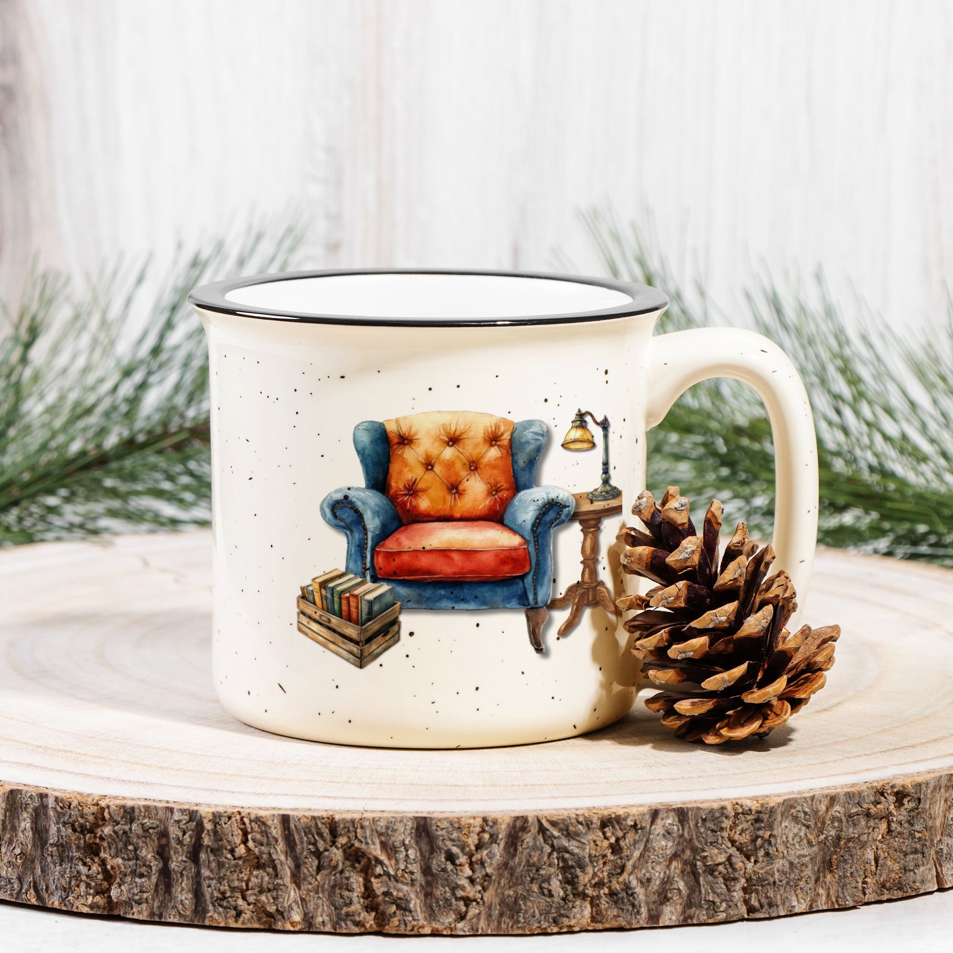 Mug with armchair design on a wooden surface with a pine cone and evergreen branches.
