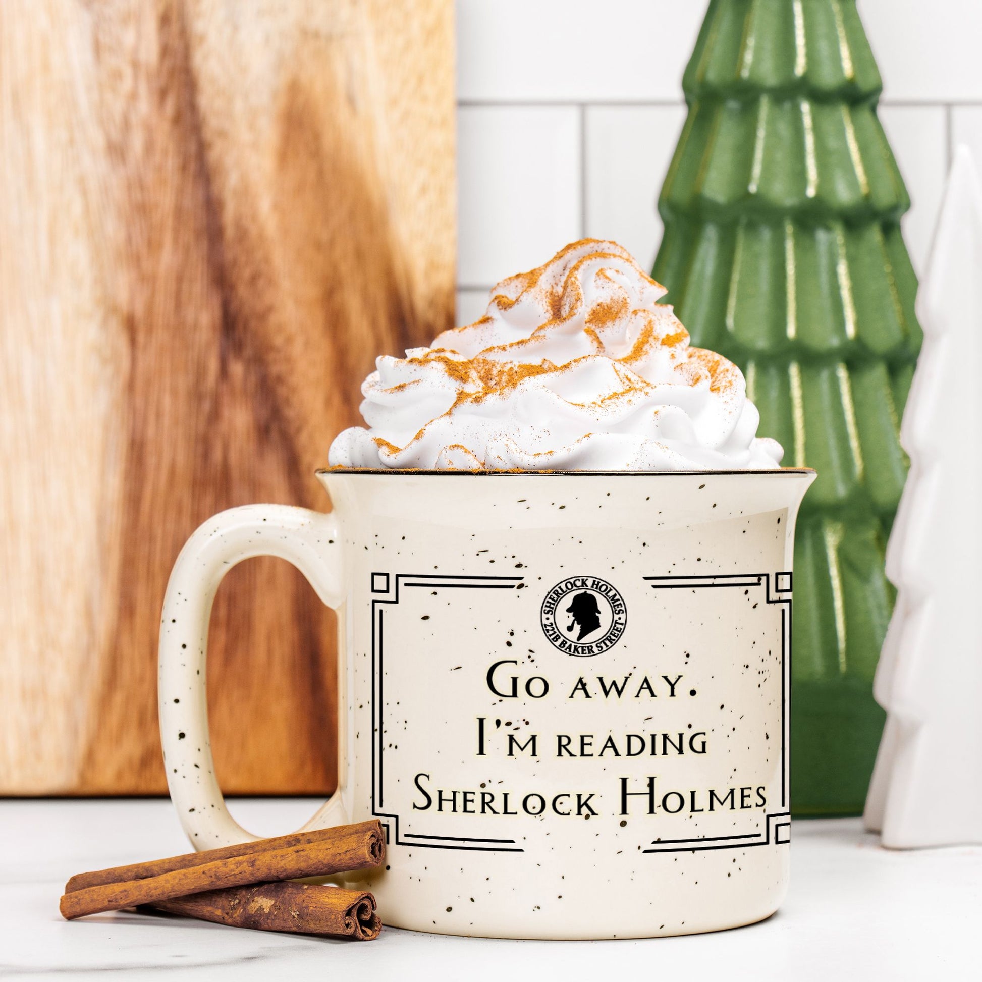 Mug with 'Go away, I'm reading Sherlock Holmes' text, topped with whipped cream and a cinnamon stick.