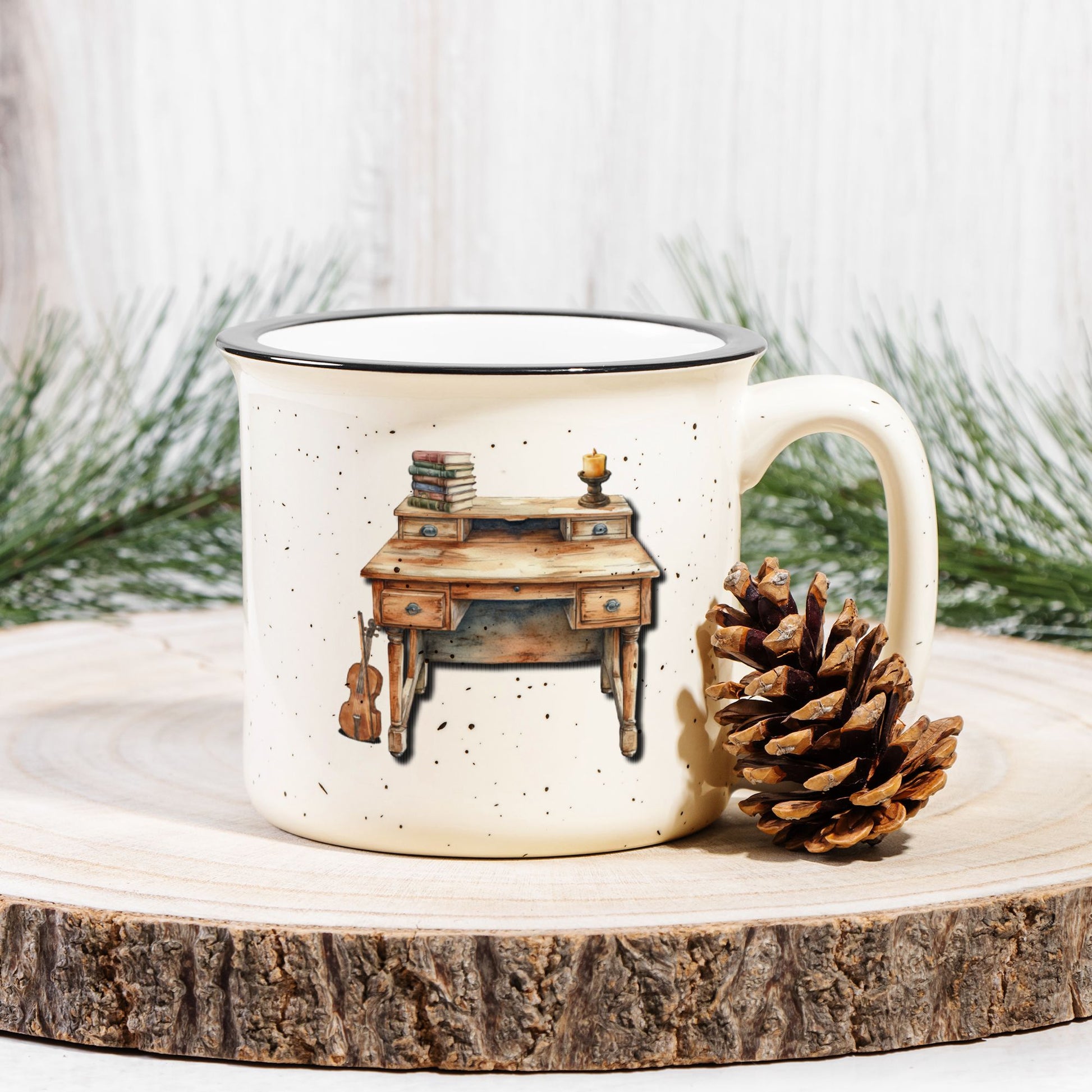 Mug with a desk illustration on a wooden surface with a pine cone and evergreen branches.